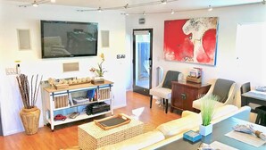 Een moderne woonkamer met een flatscreen televisie, een abstract schilderij in rood en een bank.