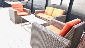 Een terras met rieten meubels, waaronder twee banken en een tafel, en een hangmat.