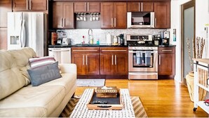 Een moderne keuken met donkere houten kasten, roestvrijstalen apparatuur en een marmeren aanrecht.