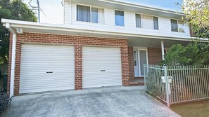 Une maison à deux étages avec un garage et une cour avant clôturée.