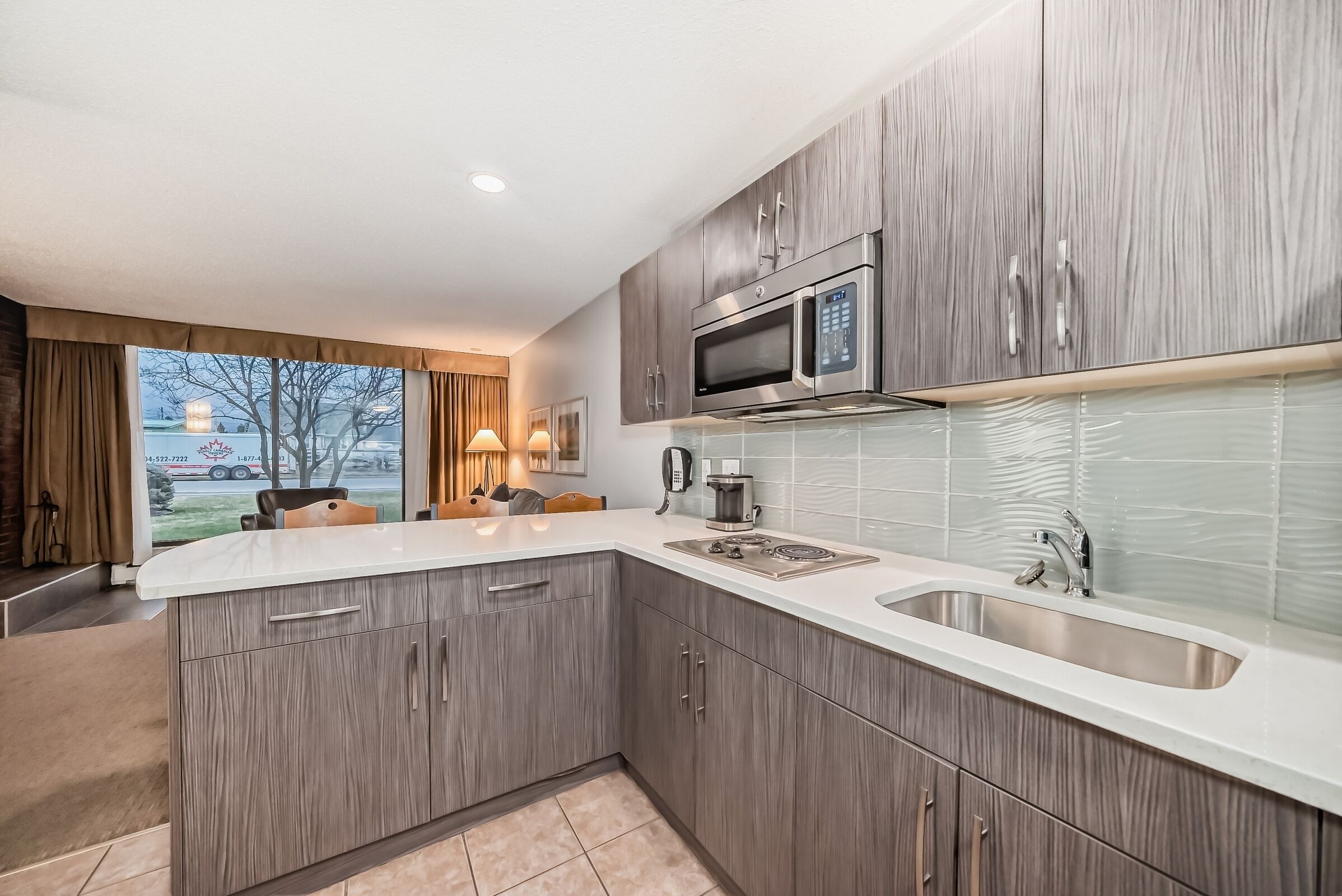 A modern kitchen with grey cabinets, a stainless steel sink, and a built-in microwave.