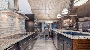 A modern kitchen with a central island, built-in appliances, and pendant lighting.