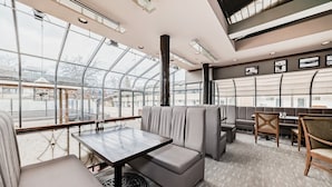 A modern indoor seating area with a glass ceiling, cushioned seating, and a table.
