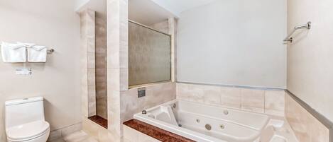 A modern bathroom with a toilet, a bathtub, and a shower area.