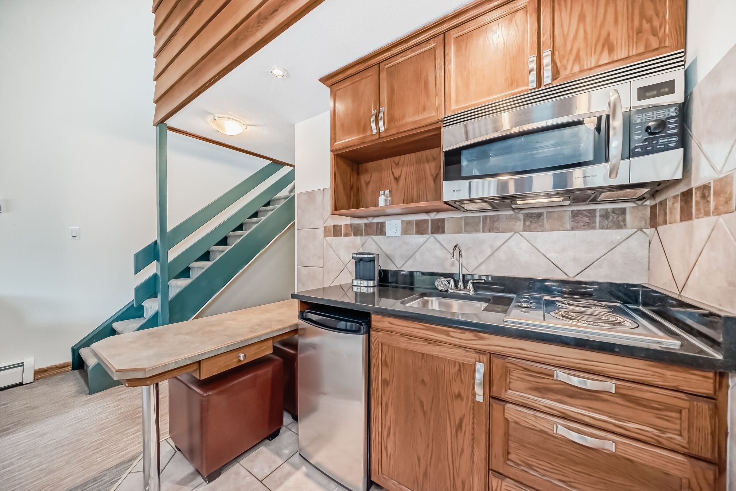 A kitchen with wooden cabinets, a stainless steel microwave, and a dishwasher.