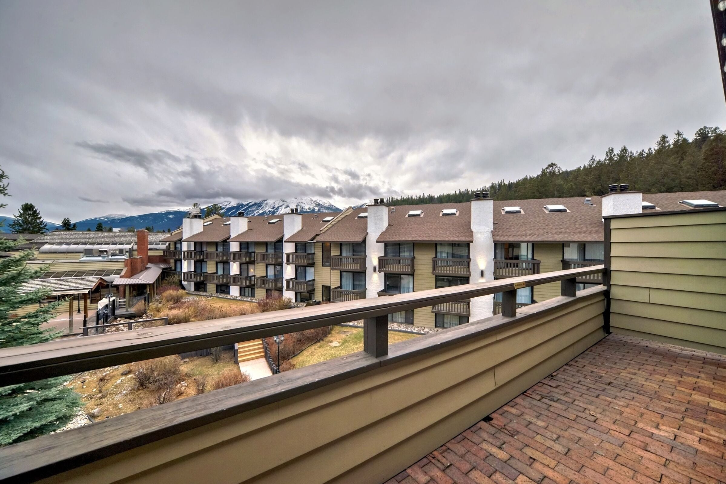 A residential building with multiple balconies, a brick pathway, and a view of a mountain range.