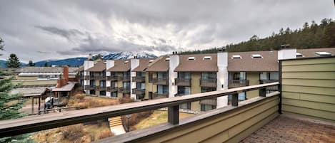 A residential building with multiple balconies, a brick pathway, and a view of a mountain range.