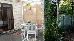 Une terrasse avec une table et des chaises, une porte-fenêtre coulissante et un espace couvert agrémenté d’un treillage.