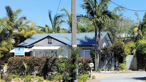 Une maison dotée d’un toit à pignon, entourée d’une végétation tropicale luxuriante.