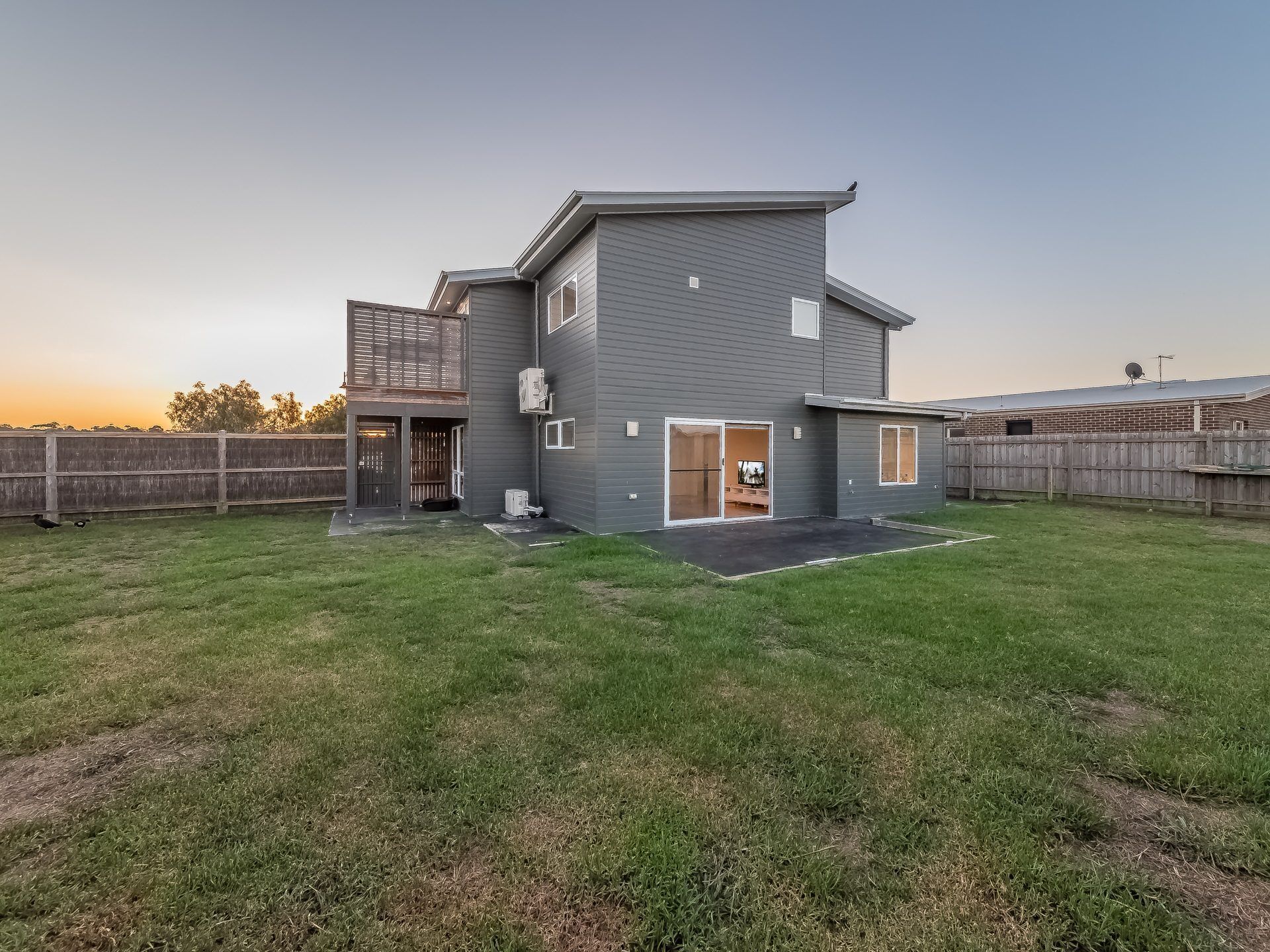 A two-story house with a fenced backyard, a covered patio, and a satellite dish.