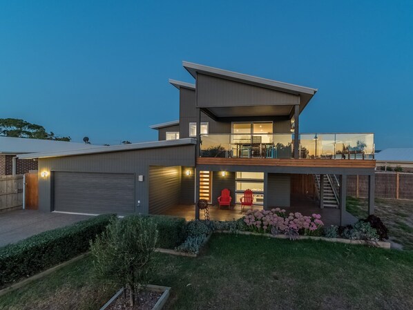 A modern two-story house with a covered patio, a garage, and a well-maintained garden.