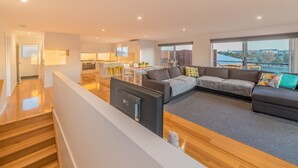Ein modernes Wohnzimmer mit einer großen Eckcouch, einem Fernseher und einem Essbereich mit Tisch und Stühlen.