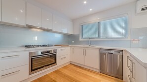 Eine moderne Küche mit weißen Schränken, einem Edelstahl-Geschirrspüler und einem Backofen.