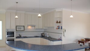 A kitchen with white cabinets, a blue countertop, and four wooden stools. - Red Rocks Road, Beach House in Cowes, bring the family! (Cowes)