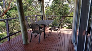A wooden deck with a table and chairs, surrounded by a railing and trees. - Red Rocks Road, Beach House in Cowes, bring the family! (Cowes)
