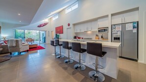 Une cuisine moderne dotée d’un îlot central, de tabourets de bar et d’un réfrigérateur décoré d’aimants.