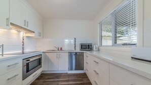 Una cocina moderna con armarios blancos, electrodomésticos de acero inoxidable y suelo de madera.