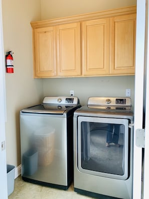 Convenient laundry area with washer and dryer, fire extinguisher for added safety.