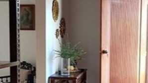 A hallway with a wooden door, a small table with a plant, and a decorative wall piece. - Apartament El Calvario at Casa Ovalle (Antigua Guatemala)