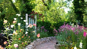 A garden pathway with a stone border, surrounded by various flowering plants and trees. - Ideal for Large Gatherings! Enjoy all that the Central Coasts offers (Atascadero)