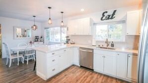 A modern kitchen with white cabinetry, a central island, pendant lighting, and a window with a view. - Ideal for Large Gatherings! Enjoy all that the Central Coasts offers (Atascadero)