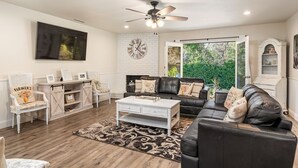 A living room with a black leather sofa, a white coffee table, and a patterned rug. There is a white wall clock and a ceiling fan. - Ideal for Large Gatherings! Enjoy all that the Central Coasts offers (Atascadero)