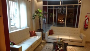 A living room with two white sofas, a glass coffee table, and a potted plant. - Hotel Luminton (Mar del Plata)