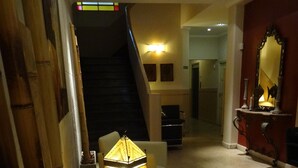 A hotel lobby with a staircase, a lit decorative lamp, a sofa, and a mirror on the wall. - Hotel Luminton (Mar del Plata)