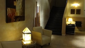 A lobby with a staircase, a lamp, a chair, and a painting on the wall. - Hotel Luminton (Mar del Plata)