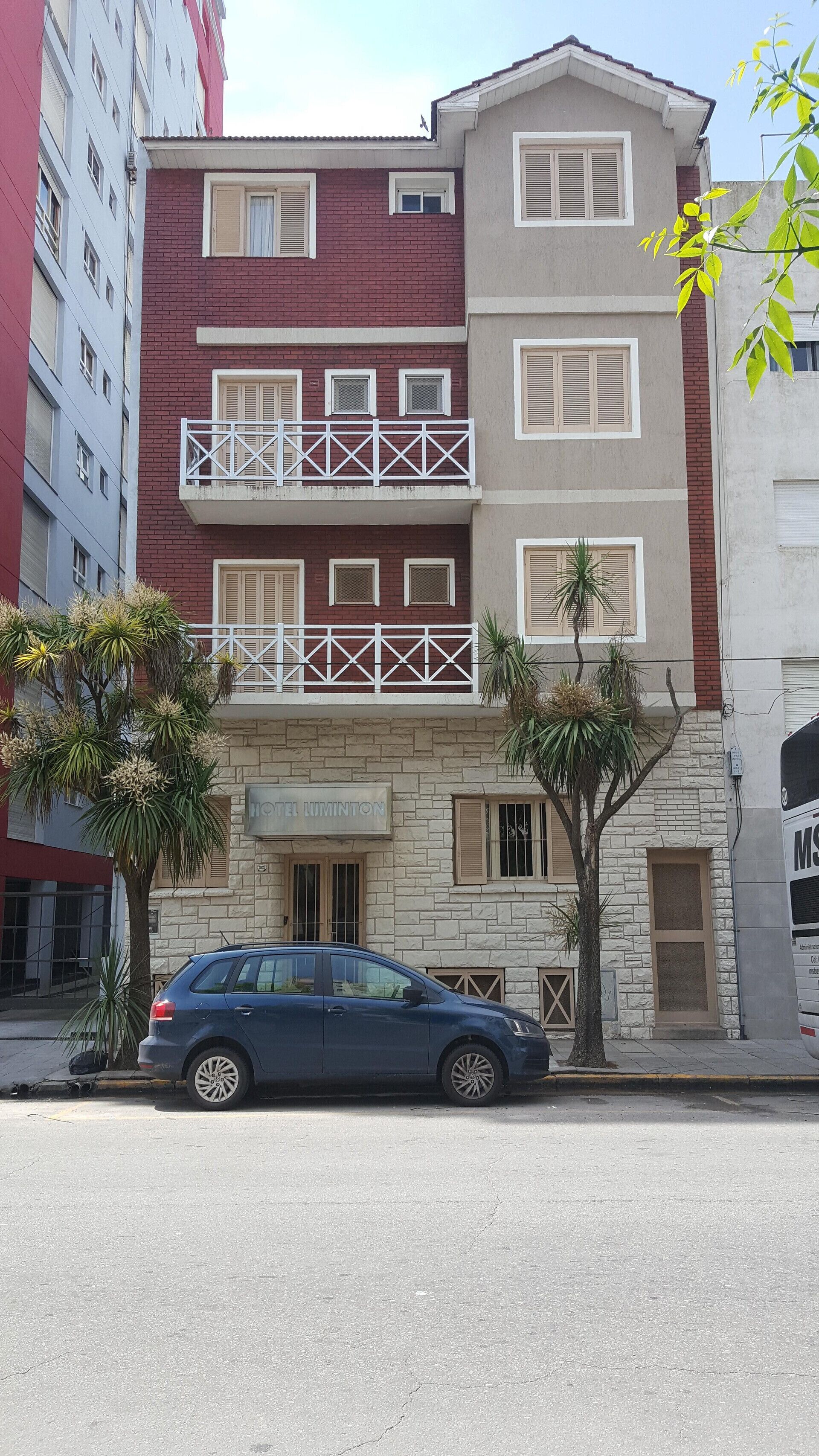Un edificio de dos pisos con fachada de piedra, un balcón con barandal blanco y un cartel que dice "HOTEL".