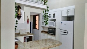 A compact kitchen with white cabinets, a built-in oven, a microwave, and a refrigerator.