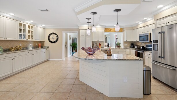 A modern kitchen with white cabinetry, a central island, stainless steel appliances, and pendant lighting. - Perfect for big family reunions, sport teams! (Fort Myers)