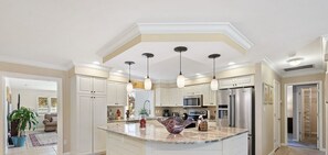 Une cuisine moderne avec des armoires blanches, des appareils en acier inoxydable et un grand îlot central.