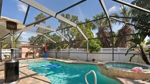 A swimming pool with a glass enclosure, a hot tub, and a poolside area with a trash can and a blue float. - Perfect for big family reunions, sport teams! (Fort Myers)