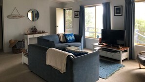 Sala de estar com sofá, televisão e janela com cortinas.