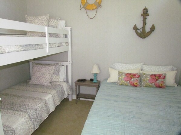Un dormitorio con literas, una mesita de noche con lámpara y elementos decorativos en la pared.