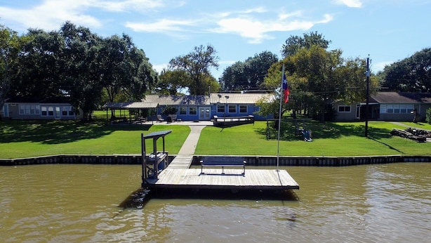 A lakeside property with a dock, a covered seating area, and a flagpole.