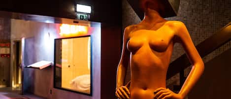 A mannequin in a room with a bed and a window.