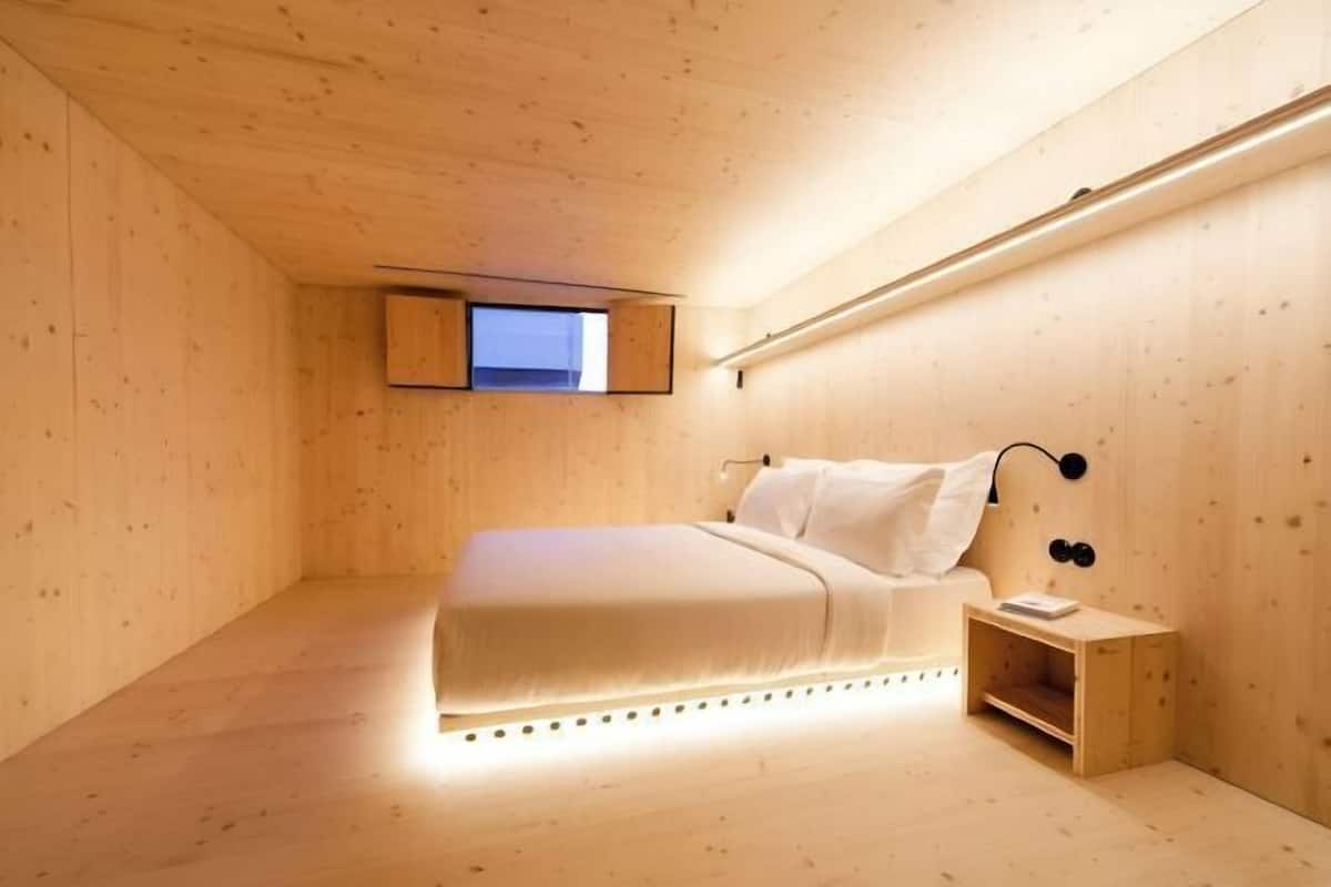 A bedroom with a bed, bedside table, and a small window.