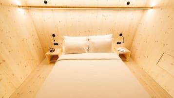 A wooden-paneled room with a bed, two bedside tables, and a nightstand.