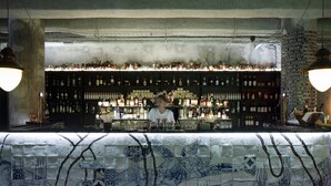 Un bar con mostrador de azulejos y estantes llenos de botellas.