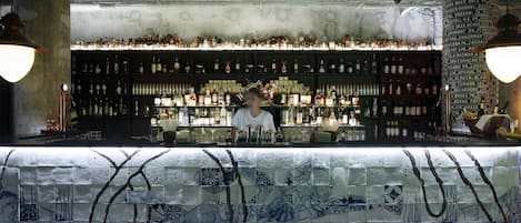 A bar with a tiled counter and shelves of bottles.