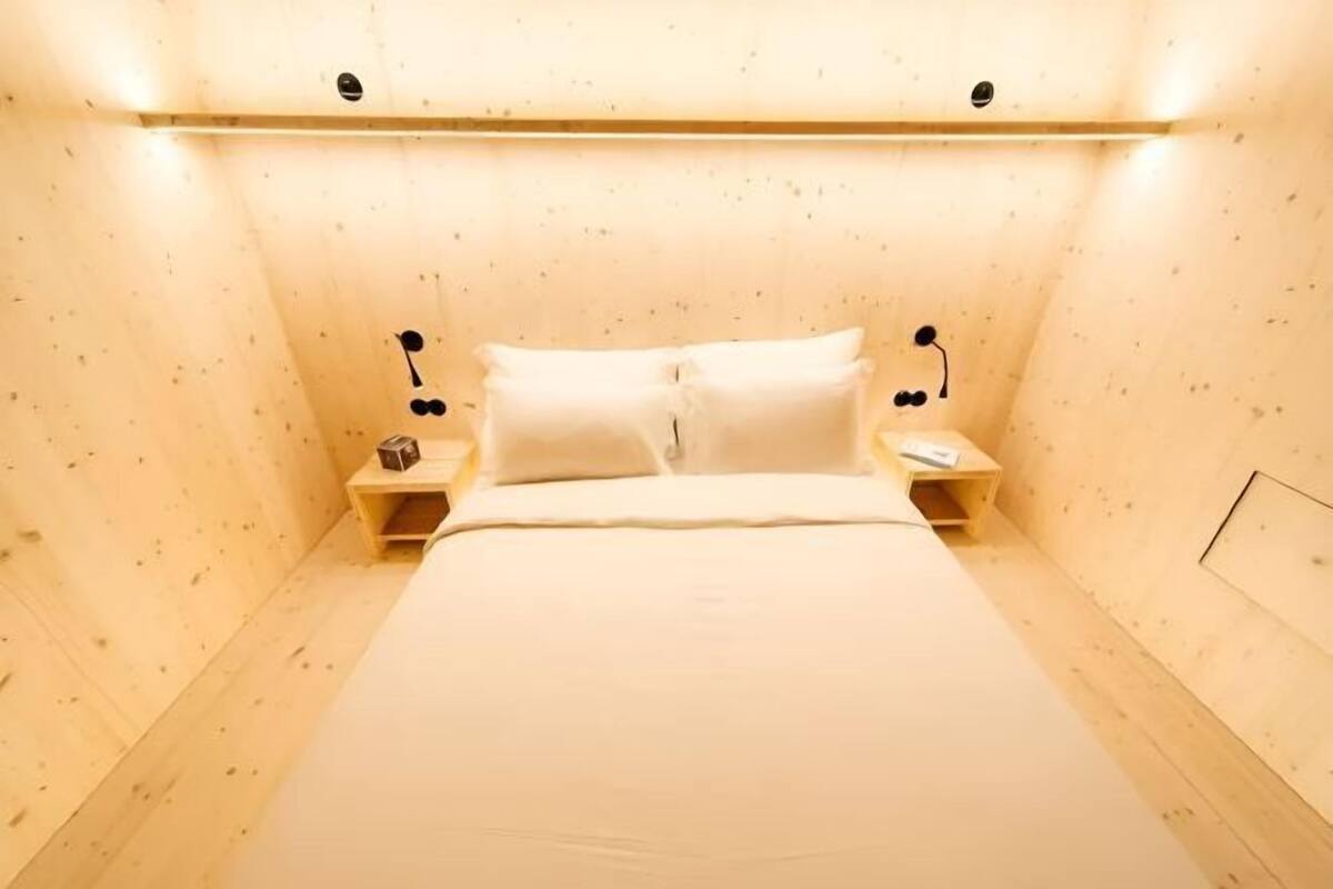A room with a bed, two bedside tables, and a headboard.