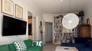 Un soggiorno con un divano verde, un tavolino in legno, una libreria e un televisore.