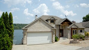 A two-story house with a garage, a small porch, and a view of a lake. - Luxurious 5 bedroom, 5+ baths, gourmet kitchen, great location (Camdenton)