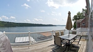 A deck with a table and chairs overlooking a lake, a white railing, and a building with a brick facade. - Luxurious 5 bedroom, 5+ baths, gourmet kitchen, great location (Camdenton)