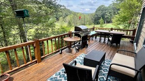 Une terrasse en bois avec des meubles d’extérieur, un barbecue et une mangeoire à oiseaux.