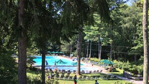 Une piscine entourée d’arbres et ombragée par des parasols.