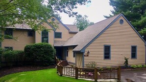 Une maison à deux étages avec un porche à l’avant et un petit jardin.
