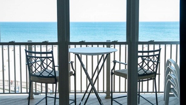 A balcony with two chairs and a table, overlooking the sea.
